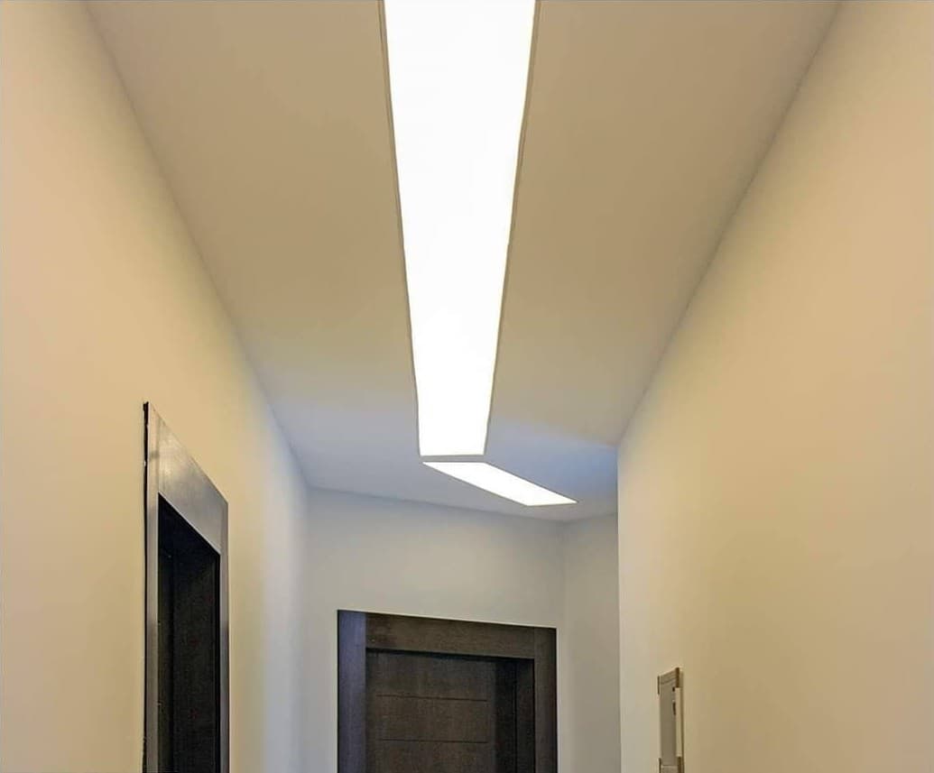 Short corridor with a backlit ceiling strip ending at a door