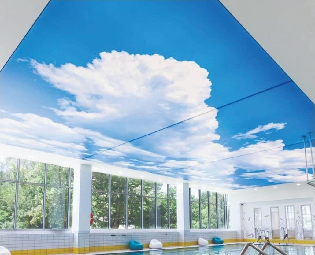 Bright printed cloud ceiling above a row of windows
