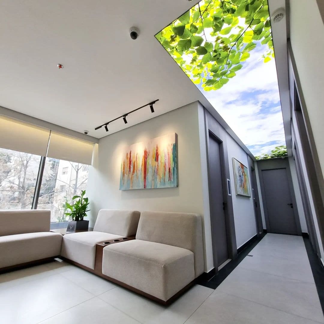 Lounge corner with a printed leaf-and-sky skylight panel