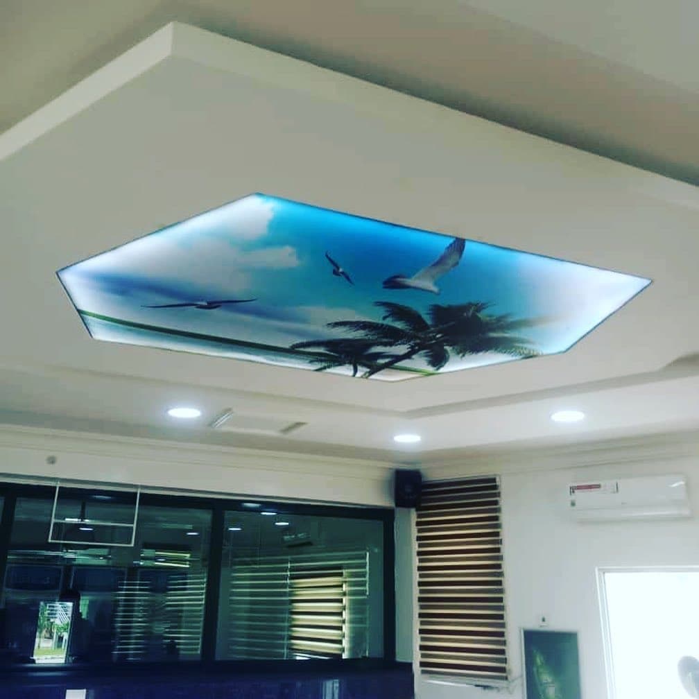 Reception with a backlit palm-and-sky printed ceiling in a stepped frame