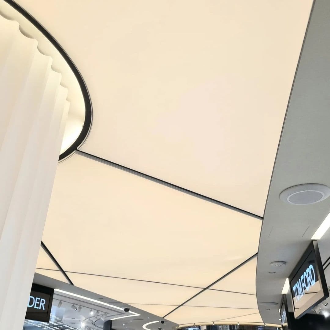 Expansive translucent ceiling with curved profile lines in a commercial interior