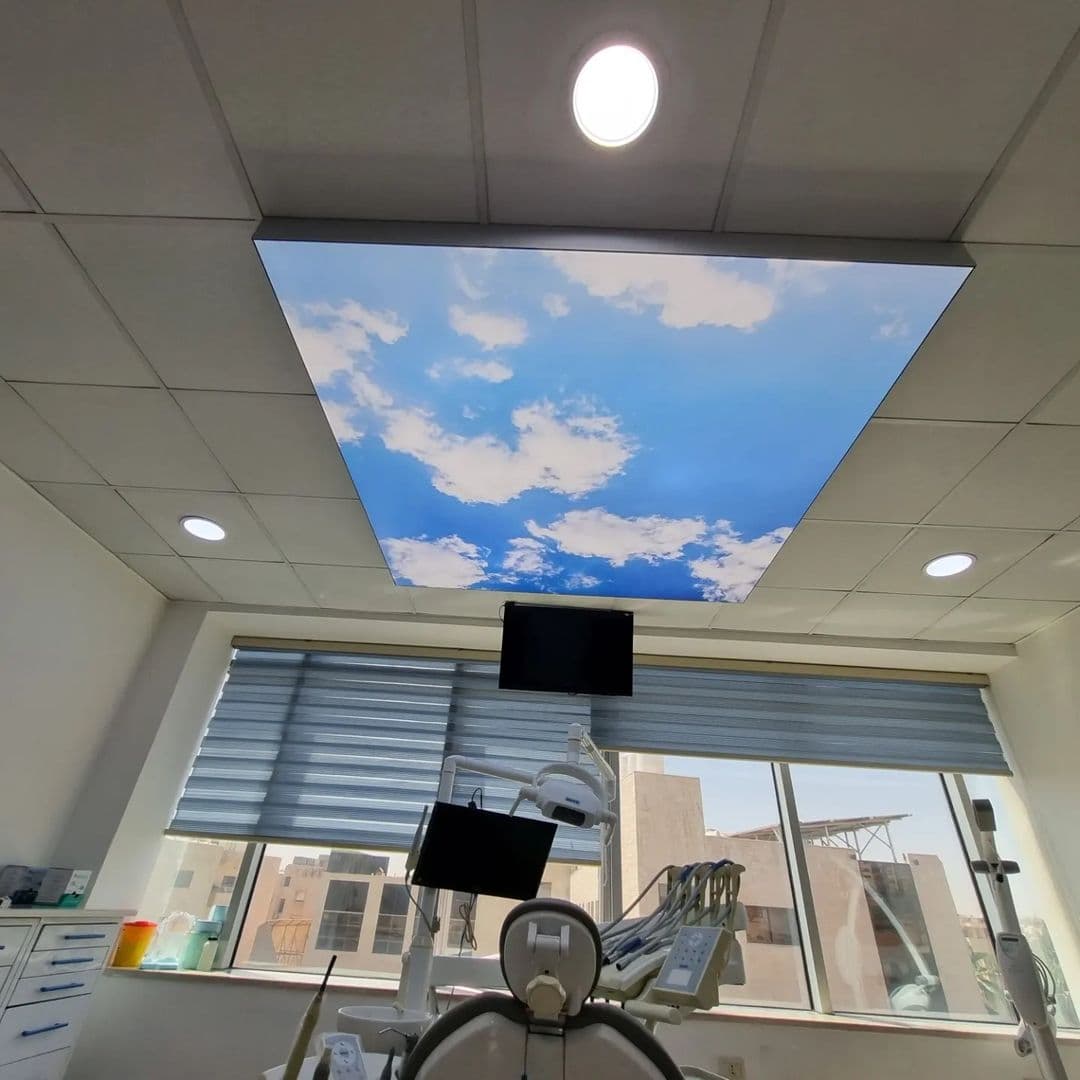 Clinic room with a printed sky panel set into a grid ceiling