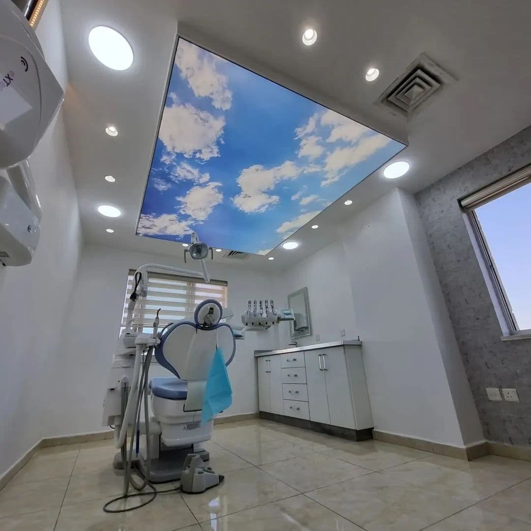 Treatment room with a printed cloud ceiling and dental chair