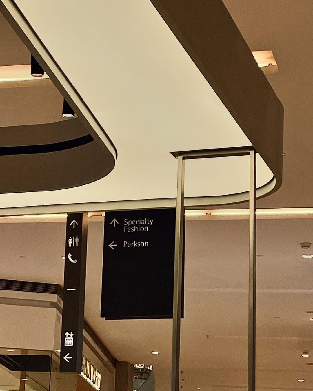 Mall walkway with curved ceiling bulkheads and wayfinding signs