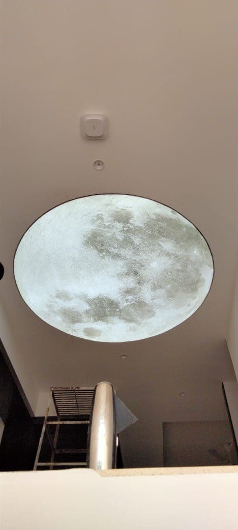 Round printed moon ceiling feature above a stairwell
