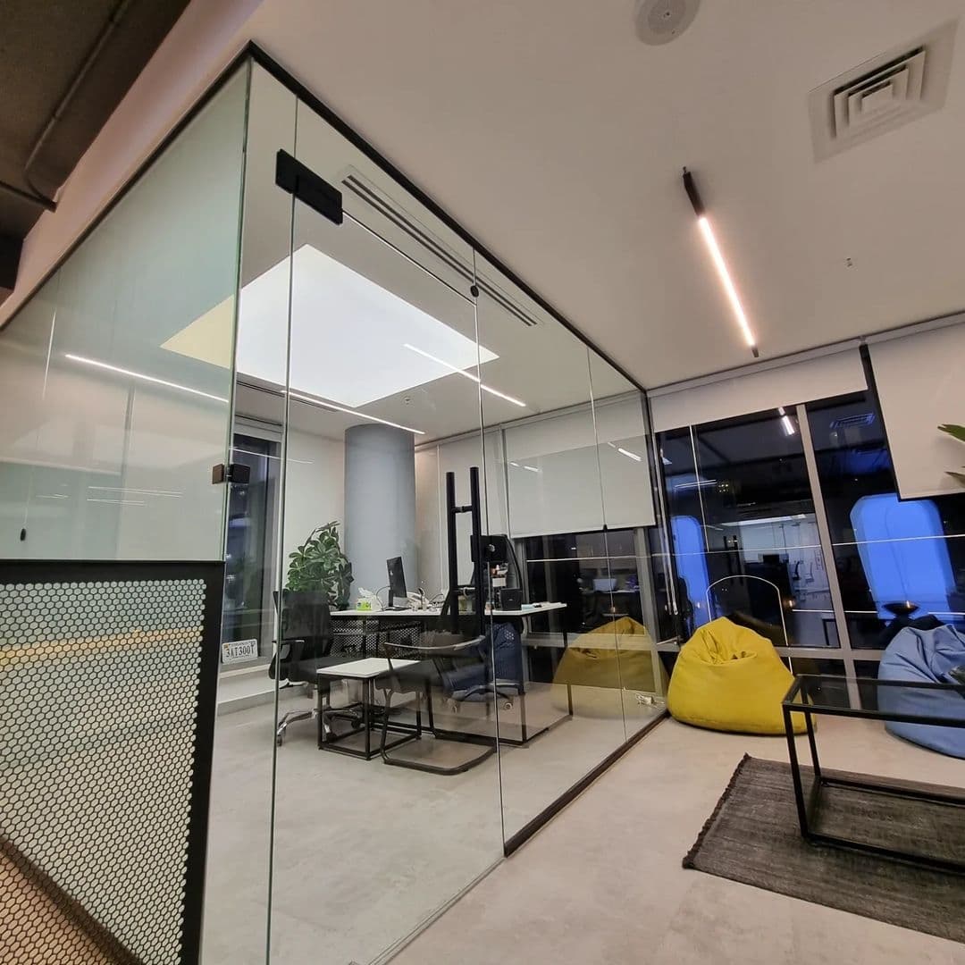 Glass cabin with a backlit ceiling panel in a modern office