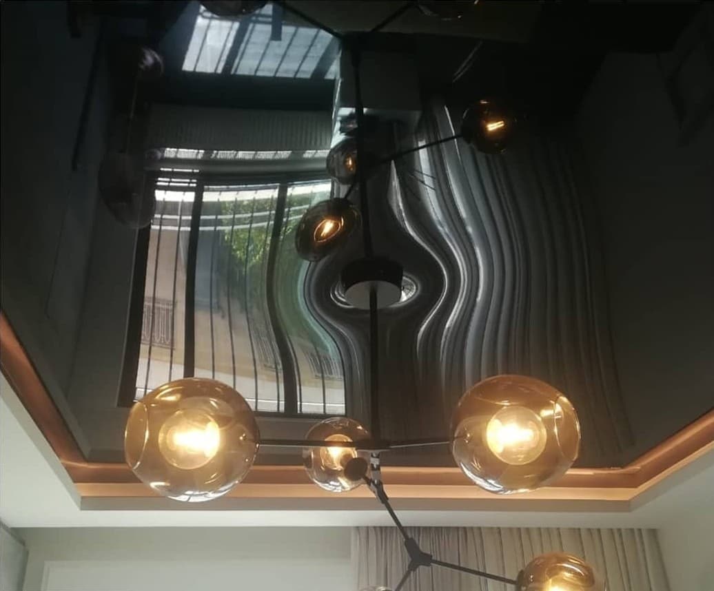 Black lacquer ceiling with globe pendant lights reflected in it
