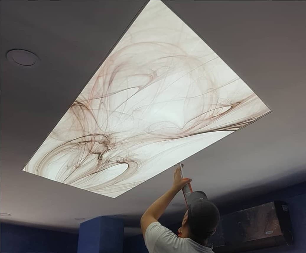 Installer fitting a printed abstract stretch ceiling panel