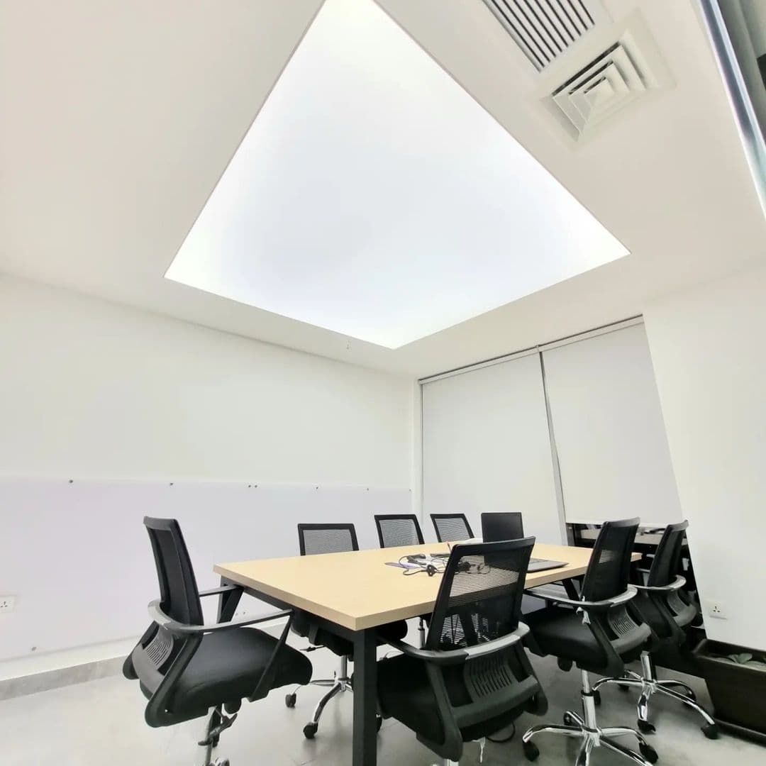 Meeting room with a large backlit translucent stretch ceiling panel above the table