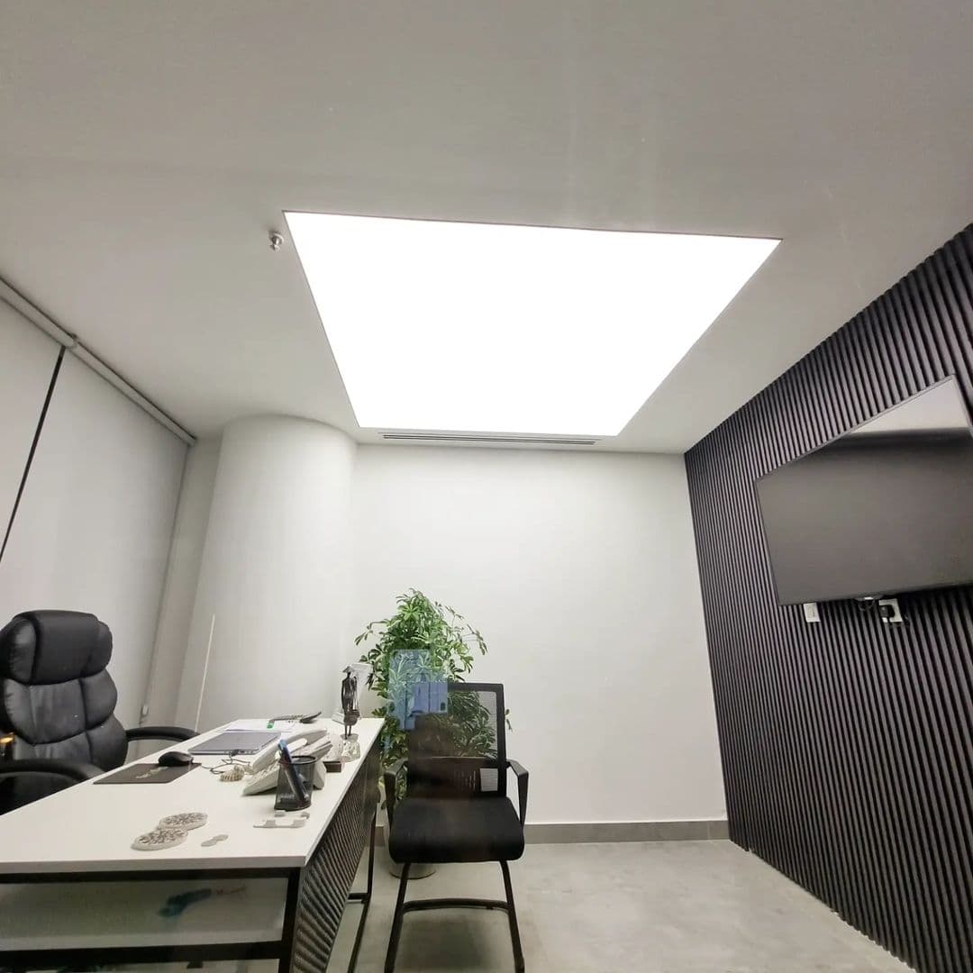 Workstation area under a bright backlit stretch ceiling panel