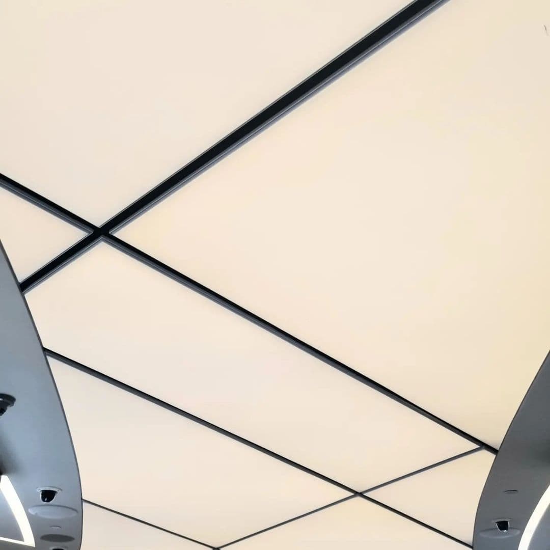 Large-format translucent stretch ceiling divided by slim black profiles