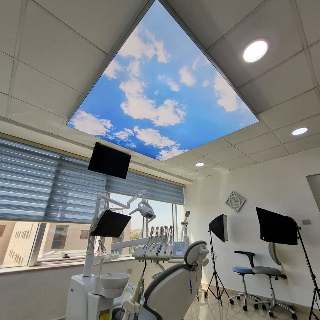 Dental treatment room with a printed sky ceiling panel above the chair