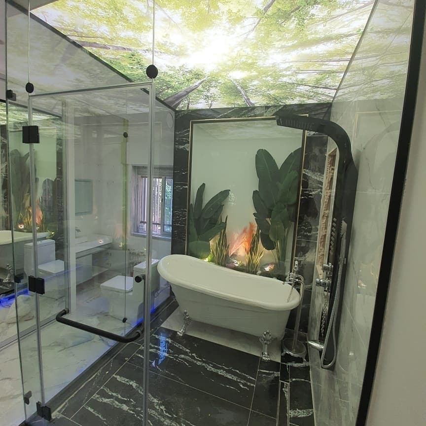 Glass bathroom with a printed tree-canopy ceiling over the bathtub