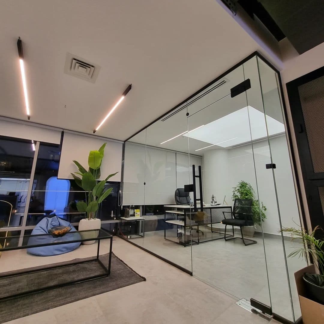 Office with glass partitions, linear lights and a backlit ceiling panel