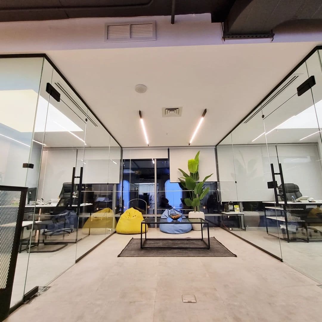 Open-plan office with glass cabins and recessed ceiling lights