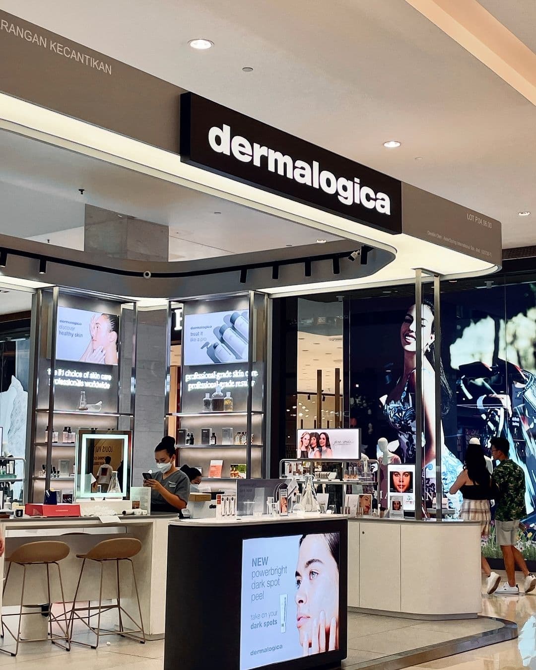 Cosmetics kiosk in a mall with a curved white ceiling canopy